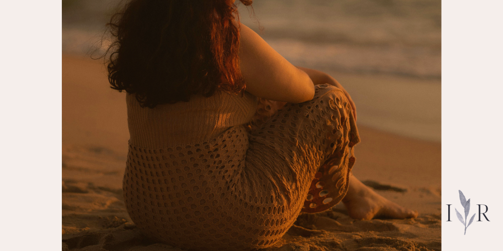 person sitting quietly on a beach representing the benefits of doing nothing